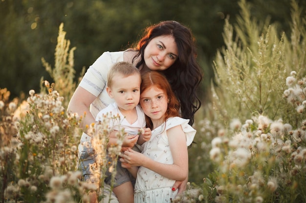 Portrait outdoors of a smiling mother loving hugging two children son and daughter