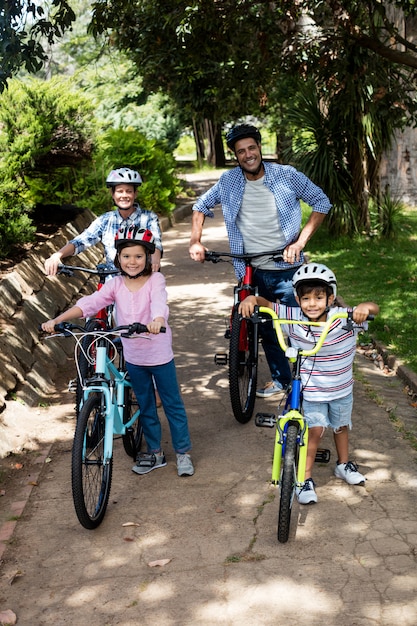 Portrait of parents and children standing with bicycle in park