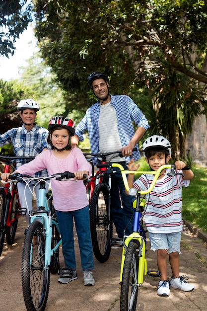 Portrait of parents and children standing with bicycle in park