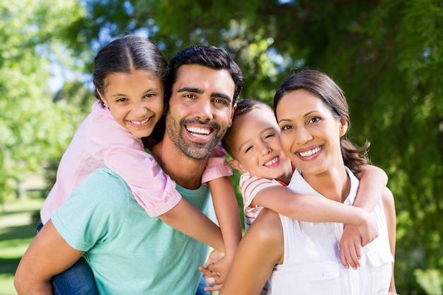 Portrait of parents giving piggy back to their kids in park