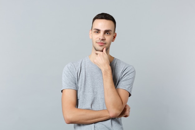 Portrait of pensive attractive young man in casual clothes put hand prop up on chin