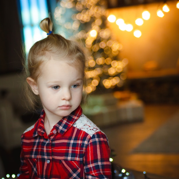 Portrait of pensive cute beautiful girl in checkered red shirt 