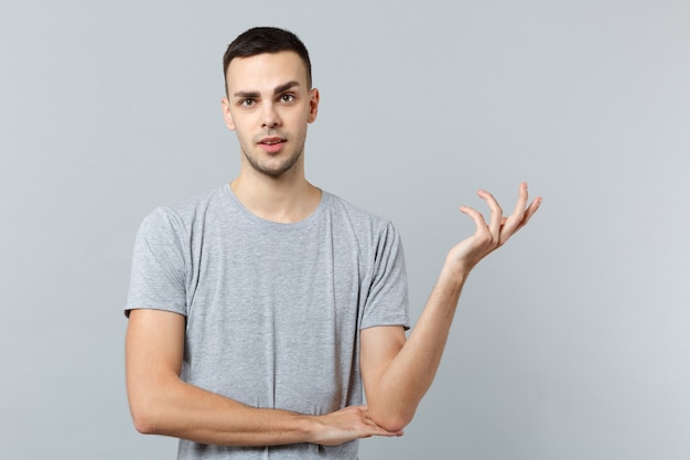 Portrait of perplexed concerned young man in casual clothes, spreading hands 