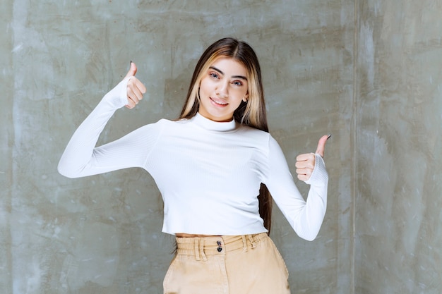 Portrait photo of a young girl model standing and showing thumbs up 