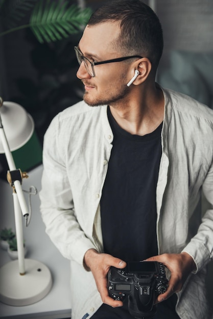 The portrait of a photographer holding the camera in his hands and looking to one side thinking abou