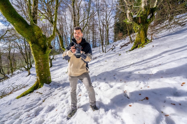 Portrait of a photographer man in snow enjoying winter photography in a beech forest