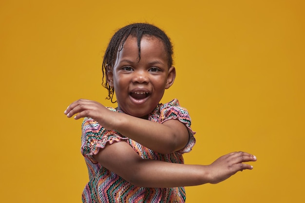 Portrait of playful african little girl fooling around against yellow background