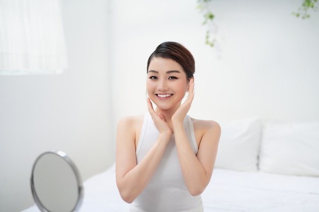 Portrait of pleased young lady touching cheek with hand.