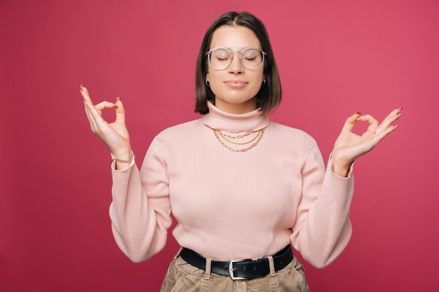 Portrait of a pleased young woman who is standing in a mudra yoga pose