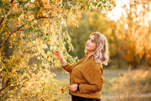 Portrait of a plussize girl with a smile on the background of an autumn landscape and trees