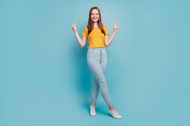 Portrait of positive charming cute lady show two v-signs posing on blue background