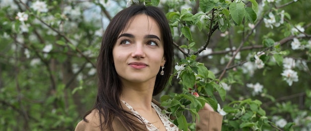 Portrait of a positive cheerful brunette girl in a green spring park