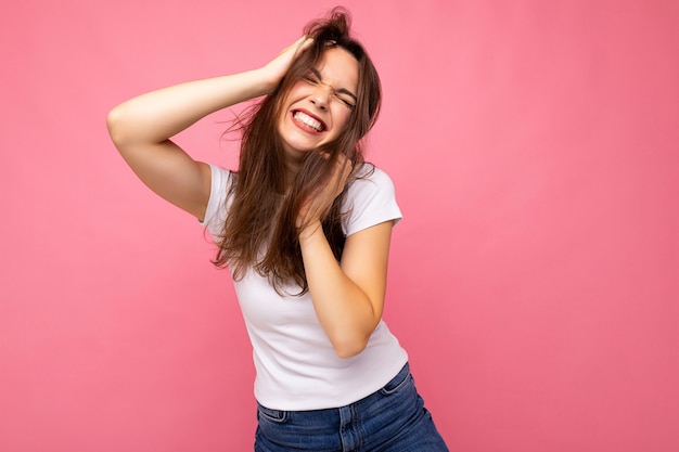 Portrait of positive cheerful fashionable woman in casual white t-shirt for mock up isolated on pink