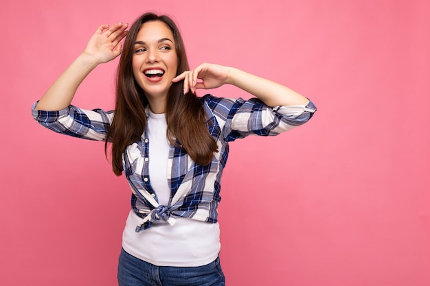 Portrait of positive cheerful fashionable woman in hipster outfit isolated on pink background with