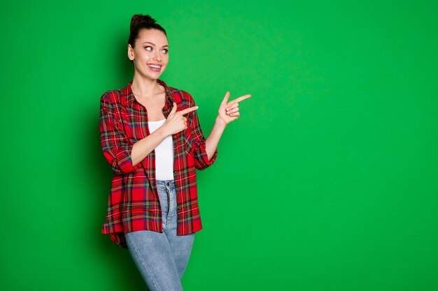 Portrait of positive cheerful girl point index finger copyspace recommend suggest select ads promotion wear denim jeans isolated over bright color background