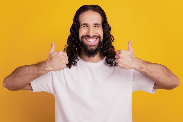 Portrait of positive cheerful man raise thumb up look camera on yellow background