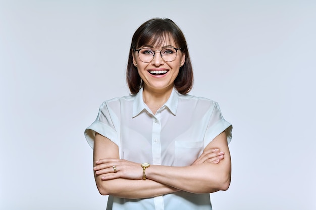 Portrait of positive confident middle aged woman looking at camera on light background