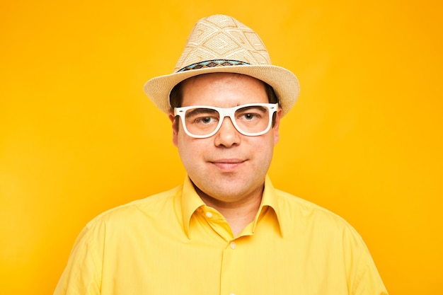 Portrait of positive fat man in hat kindly smiling isolated on yellow studio background travel vacation concept