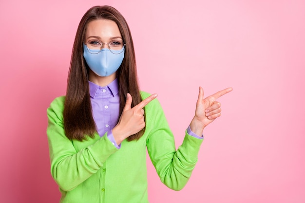 Portrait of positive girl point index finger copyspace covid news  wear respiratory mask isolated pastel color background