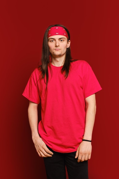 Portrait of positive guy wearing red band on head and shirt standing against red wall