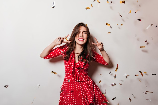 Portrait of positive lady laughing against background of confetti Brunette has fun at party and shows signs of peace