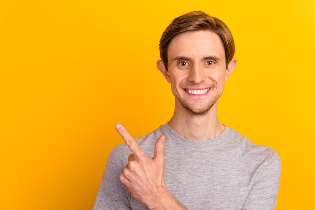 Portrait of positive man point finger empty space recommend choice isolated bright color background