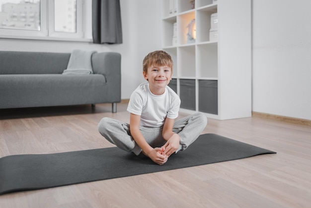 Portrait of practicing yoga Boy child doing butterfly exercise on floor on a sports mat