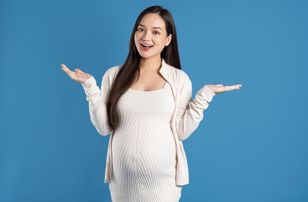 Portrait of pregnant asian woman isolated on blue background