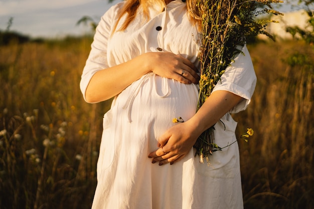 Portrait of a pregnant woman a beautiful young pregnant woman in a white dress walks in the field