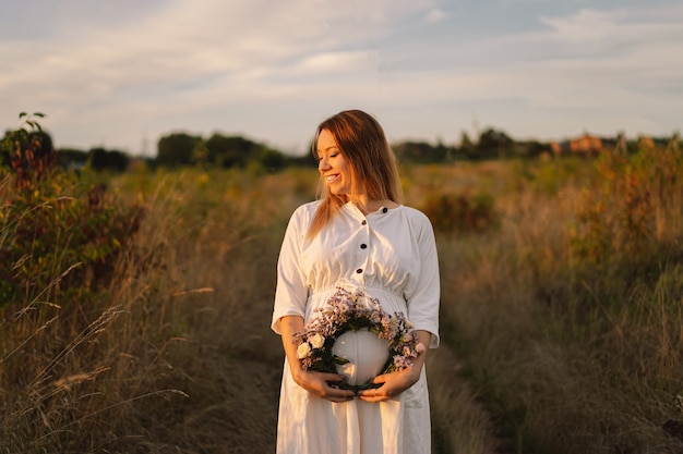 Portrait of a pregnant woman a beautiful young pregnant woman in a white dress walks in the field