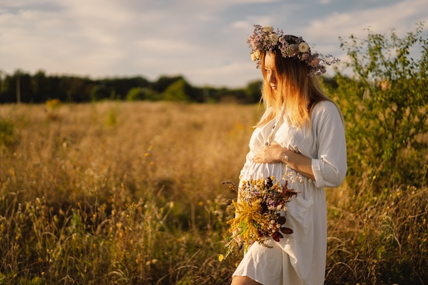 Portrait of a pregnant woman a beautiful young pregnant woman in a white dress walks in the field