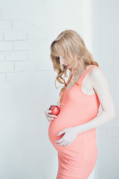 Portrait of a pregnant woman with an Apple in her hand. Calm expectant mother. Lunch break, snack