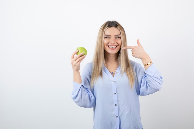 Photo portrait of a pretty attractive woman model standing and holding a green fresh apple .