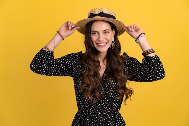 Portrait of pretty attractive woman posing isolated on yellow background wearing black dotted dress and straw hat