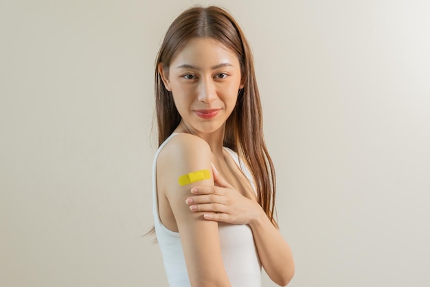 Portrait of pretty beautiful asian young teenage attractive after getting receive anti virus vaccine covid19 Showing arm on white bandage isolated on white background copy space