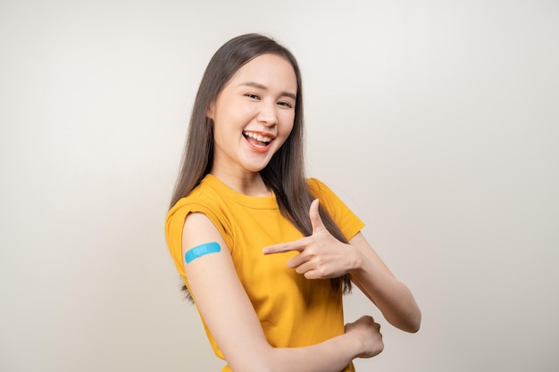 Portrait of pretty beautiful asian young teenage attractive after getting receive anti virus vaccine covid19 Showing arm on white bandage isolated on white background copy space