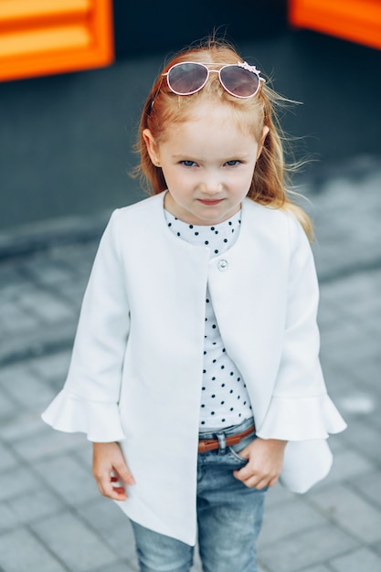 Portrait of a pretty blonde girl in white coat and blue jeans