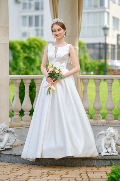 Portrait of pretty bride with coronet in hair outdoor near ceremony pavilion