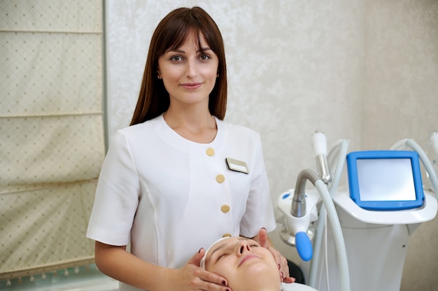 Portrait of a pretty brunette cosmetologist working at SPA salon.