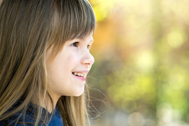 Portrait of pretty child girl with gray eyes and long fair hair smiling outdoors