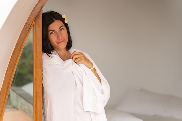 Portrait of a pretty dark-haired Caucasian woman wrapped in a sheet posing at the camera