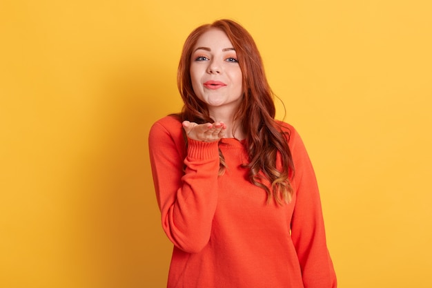 Portrait of pretty friendly girl in casual orange jumper