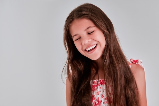 Portrait of a pretty girl on a gray background, she closed her eyes in pleasure and smiles.