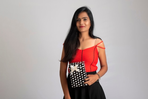 Portrait of a pretty girl holding and posing with a gift box.