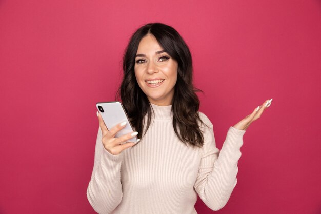 Portrait of pretty happy person using phone isolated on the pink background.