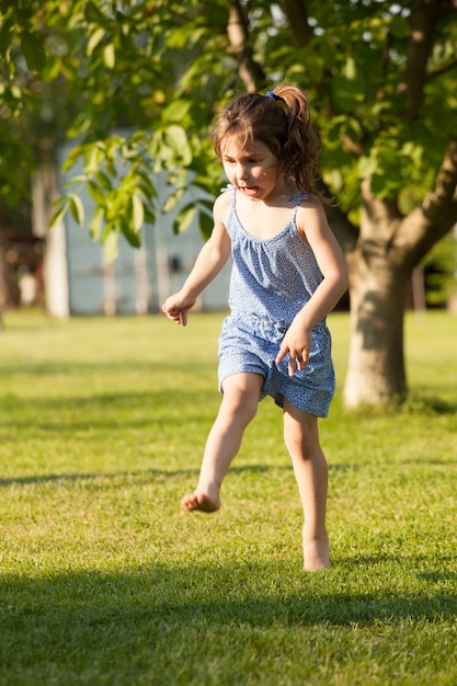 Portrait of a pretty little girl who plays with the colorful ball in the rural backyard