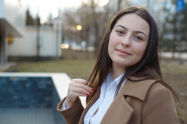 Portrait of a pretty smiling girl, outside. Official dressed woman, smiling and being happy. Close-up portrait.