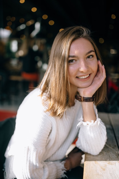 Portrait of a pretty smiling girl with blurred cafe background