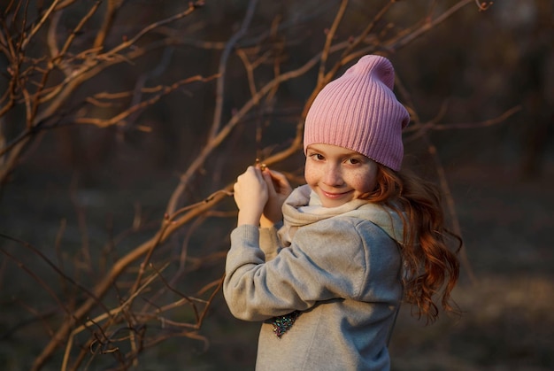 Portrait of a pretty smiling girl with red hair and freckles in spring or in the fall with twigs