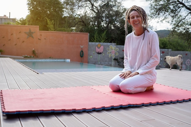 Portrait of a pretty smiling woman with dreadlocks, cheerfully looking at the camera outdoors.